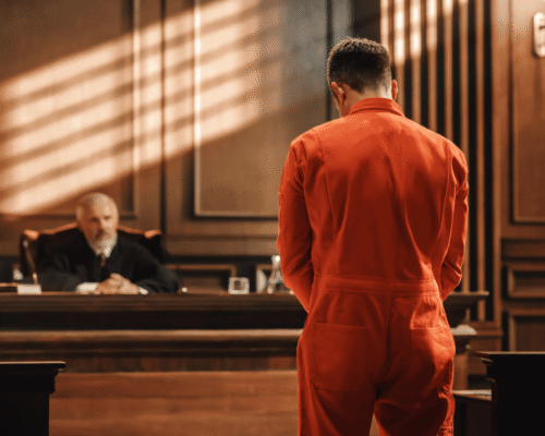 Defendant in an orange jumpsuit standing before a judge during a court proceeding, illustrating the moment of criminal sentencing San Diego.