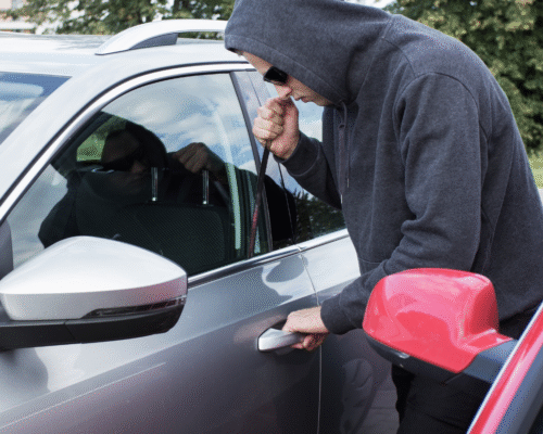 A person attempting to break into a parked vehicle, illustrating allegations of theft and how prior convictions can affect grand theft sentencing under California law.