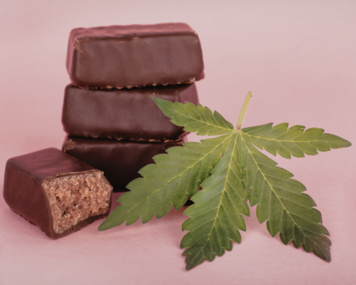 Chocolate edibles stacked beside a cannabis leaf, with one piece cut open, representing marijuana consumption and the legal risks of driving under the influence of edibles in Escondido, California.