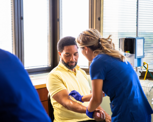 Medical professional drawing blood from a seated patient in a clinical setting, illustrating post-accident blood testing and the legal implications of DUI investigations in California, including consent laws and forced blood draw procedures.