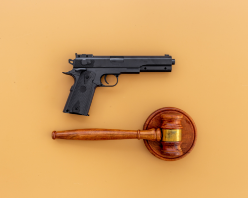 A judge’s gavel and a handgun placed side by side on a neutral background, symbolizing the intersection of firearm rights and legal restrictions in domestic violence cases.