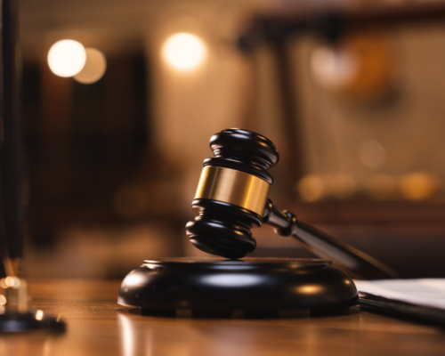 Close-up of a judge’s gavel resting on a sound block inside a courtroom, representing the criminal justice process, court proceedings, and legal defense after an arrest or criminal charge.