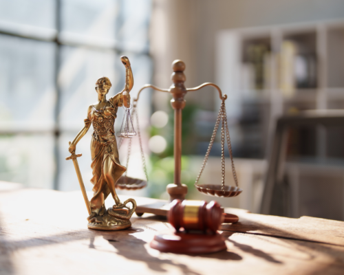 Lady Justice statue, balanced scales, and a judge’s gavel displayed on a desk in a law office, symbolizing criminal defense, plea bargain negotiations, and the legal decision-making process.