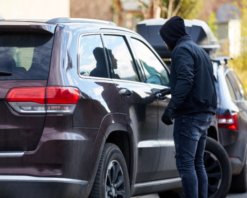 Person opening the door of a parked SUV, representing theft from a vehicle, unlawful entry, property crimes, and criminal defense involving California theft charges.