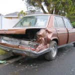 brown car parked on the street clearly damaged from being hit.