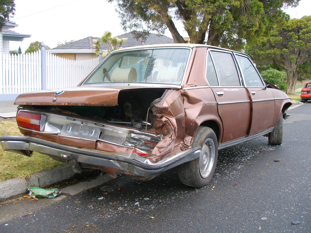 brown car parked on the street clearly damaged from being hit.