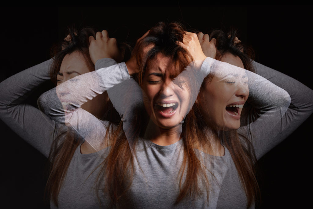 Shot of a young woman experiencing mental illness against a black background