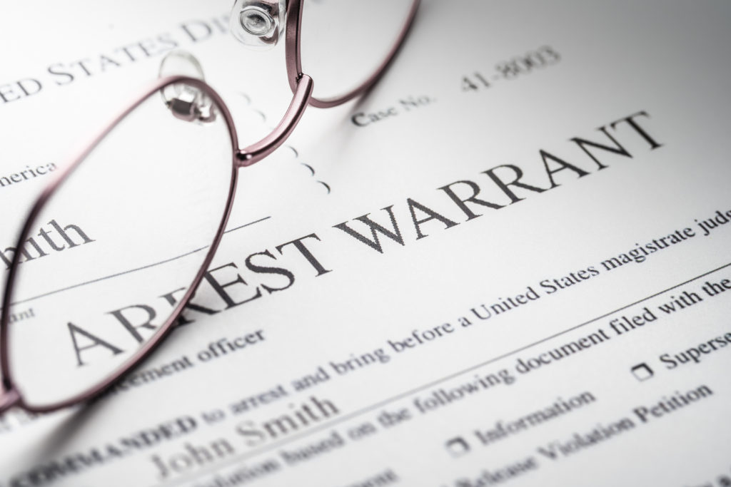 Arrest Warrant document with reading glasses