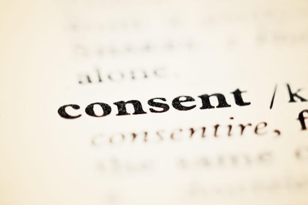 An opened dictionary or encyclopedia shows the entry for Consent