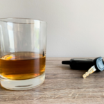 A cup of whiskey next to a set of car keys