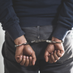 A man with his hands in handcuffs behind his back.
